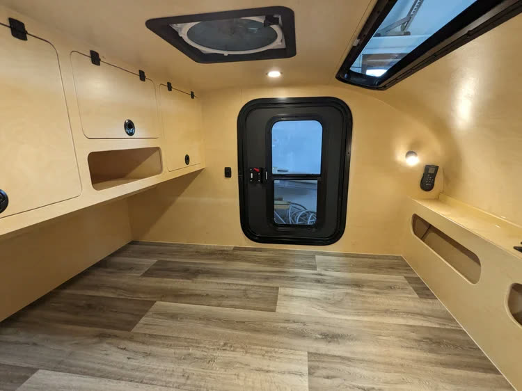 Interior acabado com armários de birch, porta preta com janela, claraboia e piso amadeirado